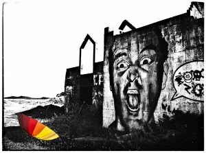schwarz-weiss-bild-von-mauer-mit-graffiti-von-schreiendem-mann-bunter-regenschirm-liegt-davor