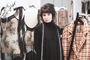 schwarzhaarige-frau-stehend-zwischen-kleiderstaender