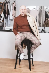 mann-mit-mantel-ueber-schulter-sitzend-auf-barhocker-vor-theke