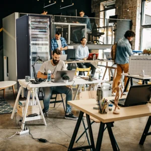 buero-mit-menscdhen-am-schreibtisch-und-serverschrank-im-hintergrund